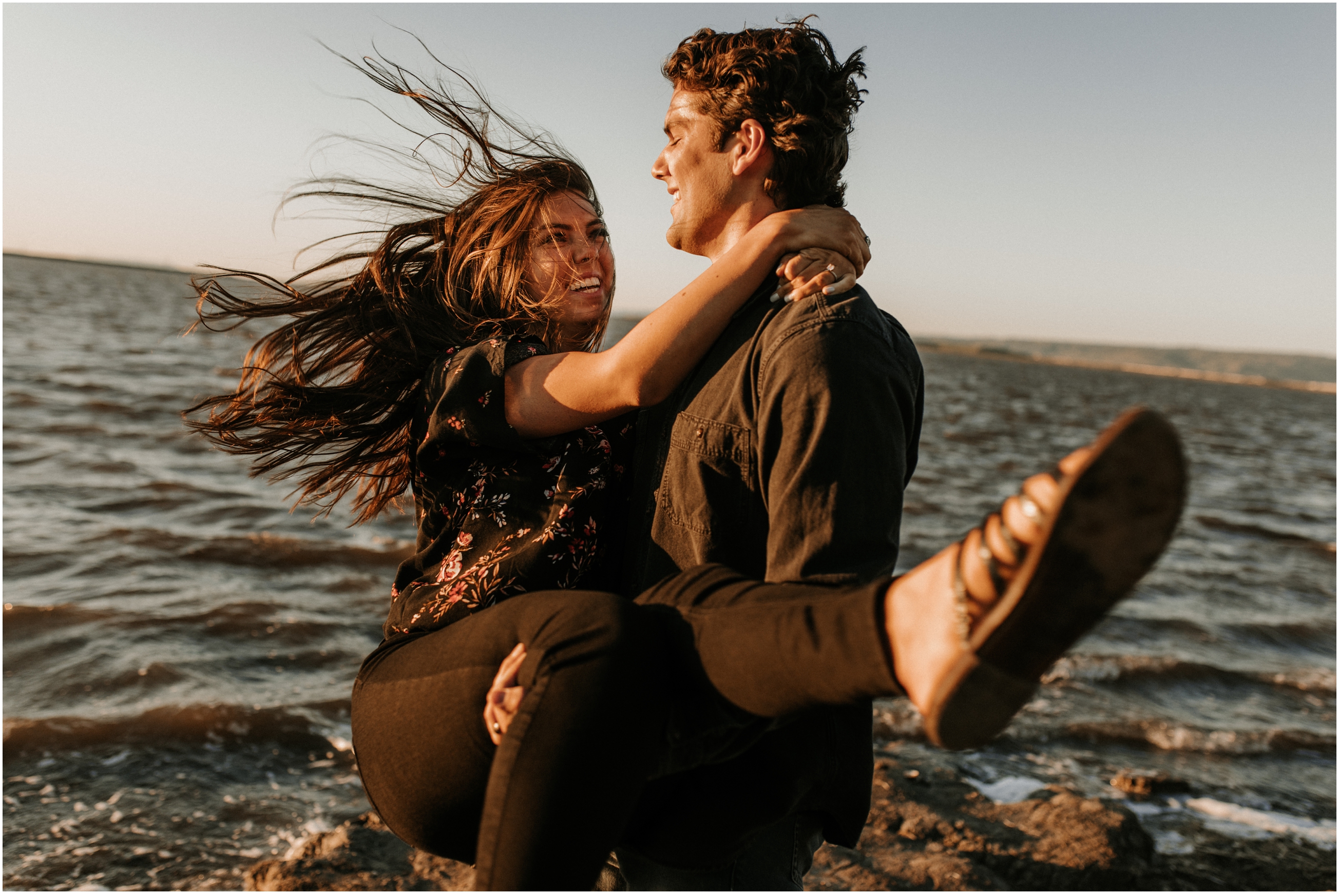 husband swinging wife around at sunset on windy beach in bay area california