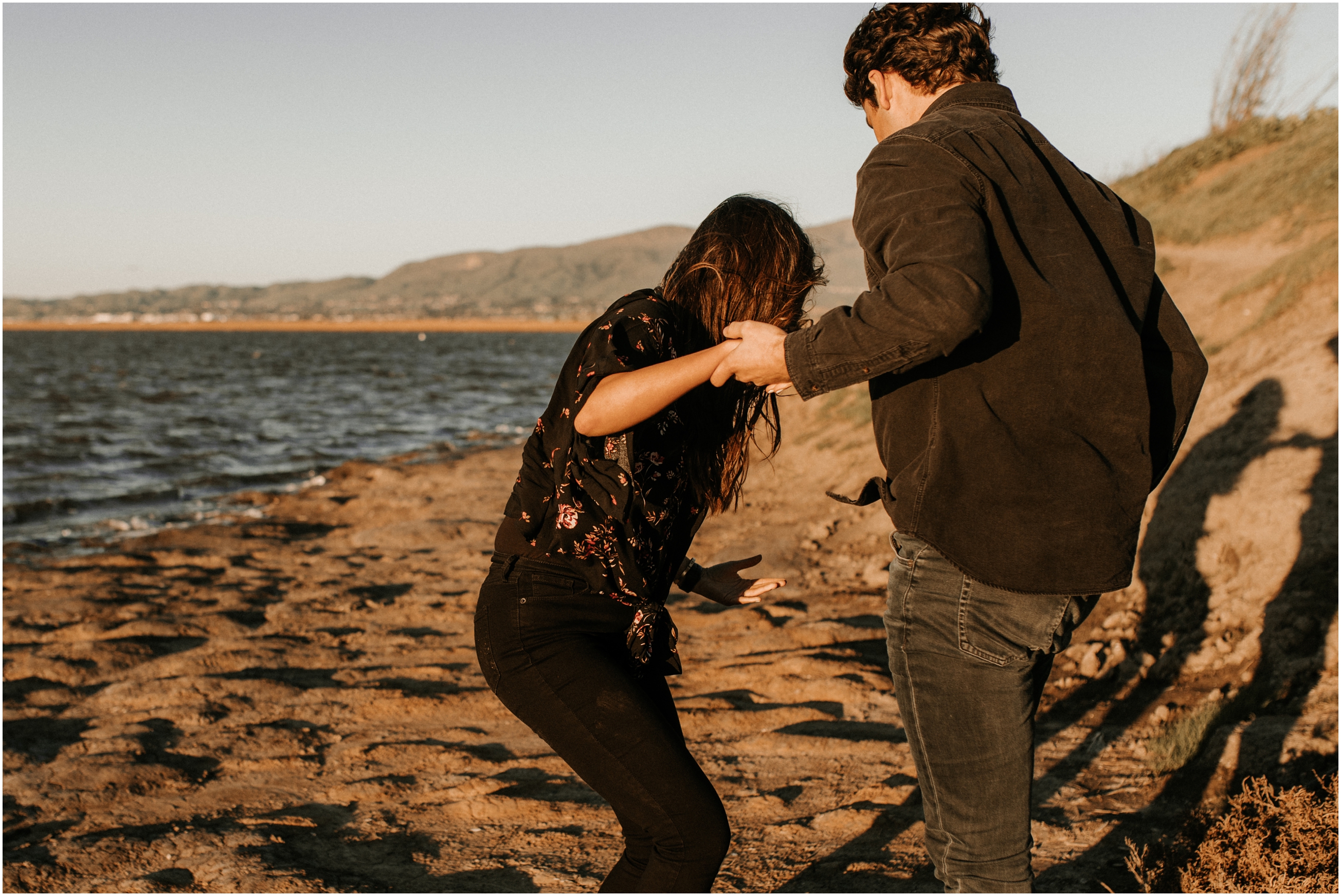husband helping wife stand up on beach in bay area california
