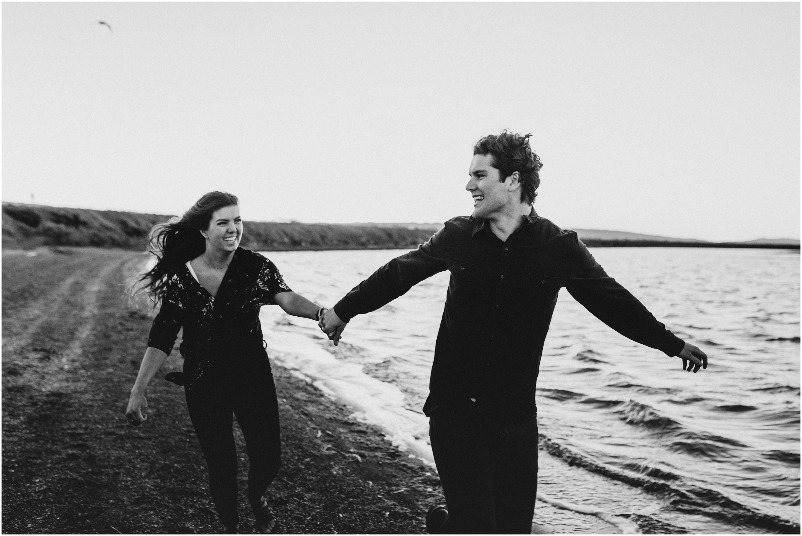 black and white couple running hand in hand toward camera