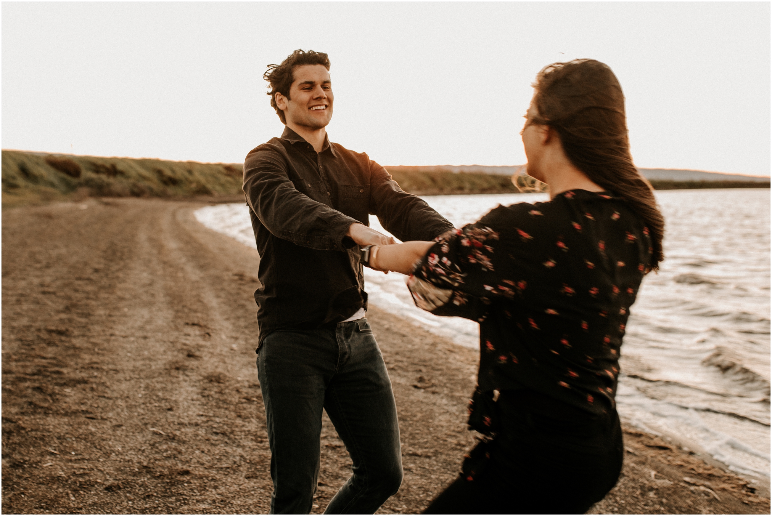 couple spinning each other around at sunset on windy beach in bay area california
