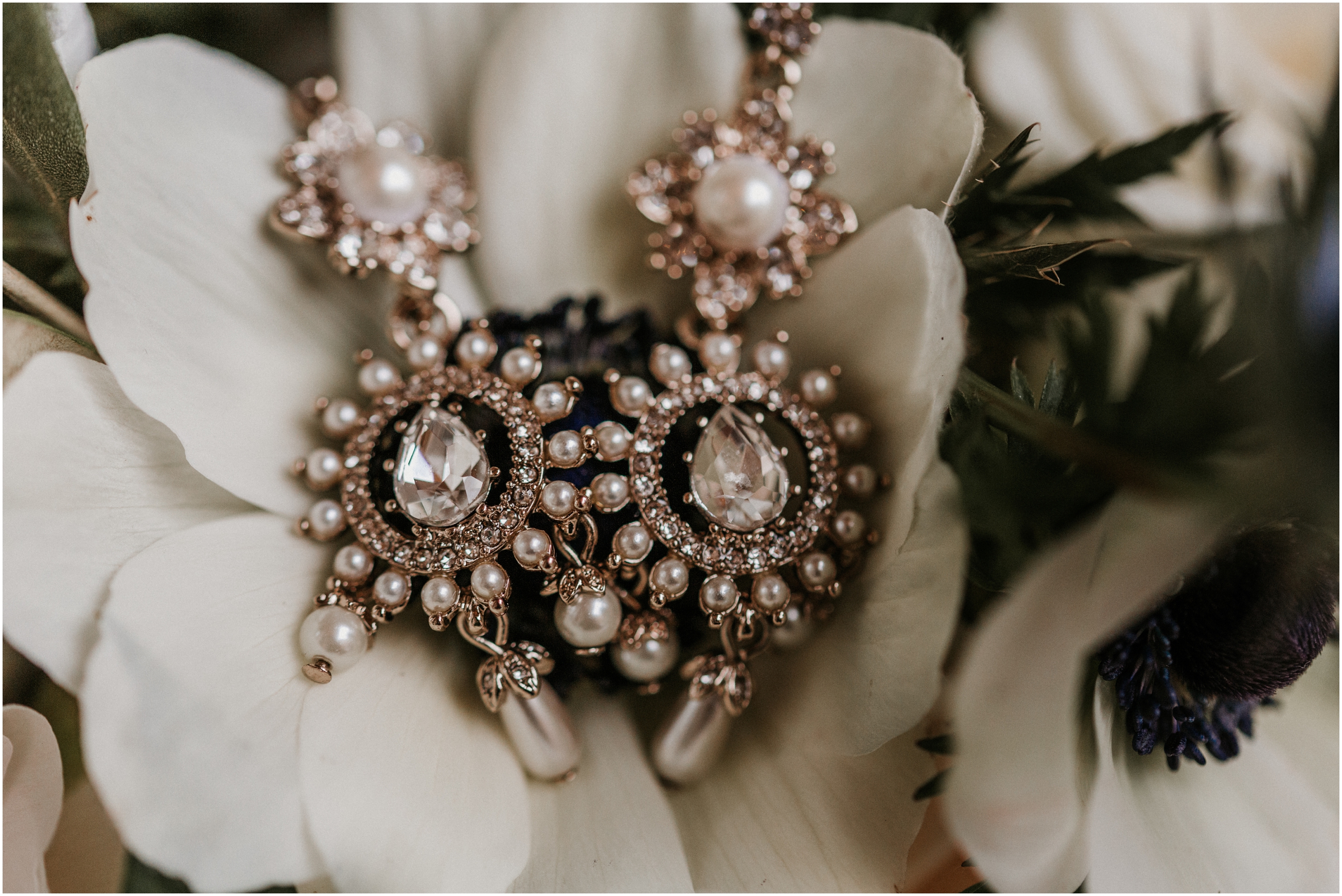 bride's wedding earrings sitting on flower in bouquet