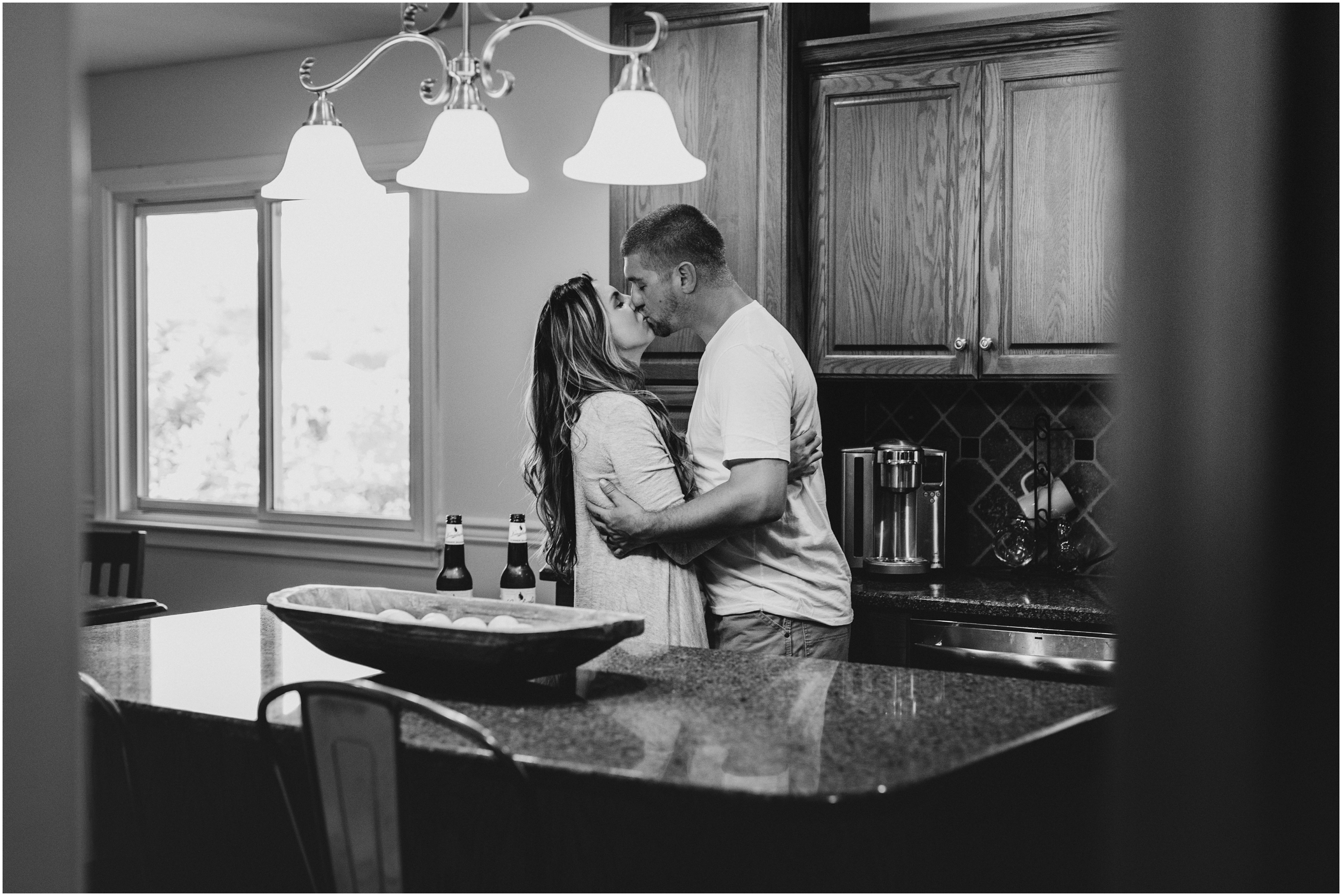 black and white image of couple kissing in kitchen