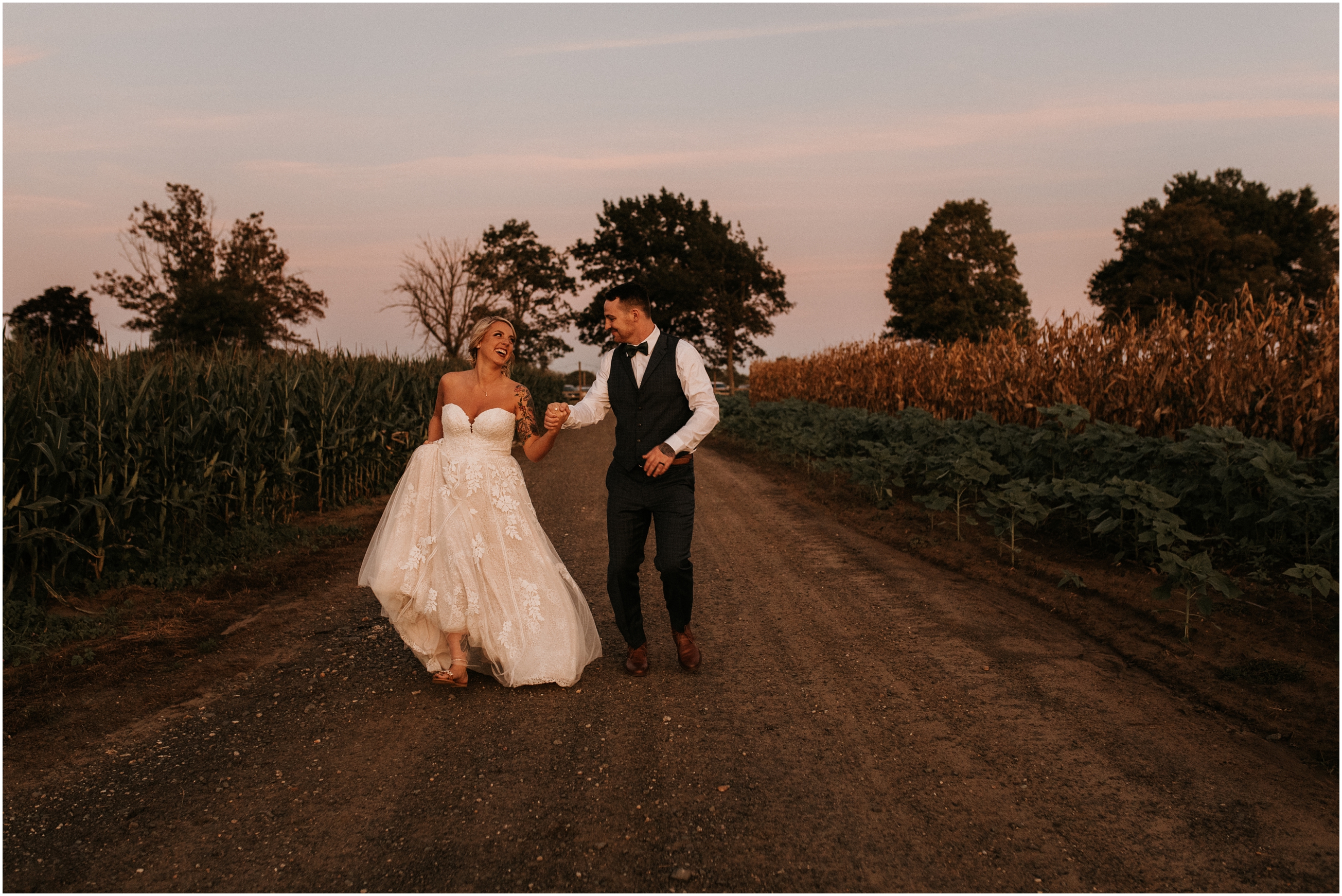 bride and groom running through farm field at sunset