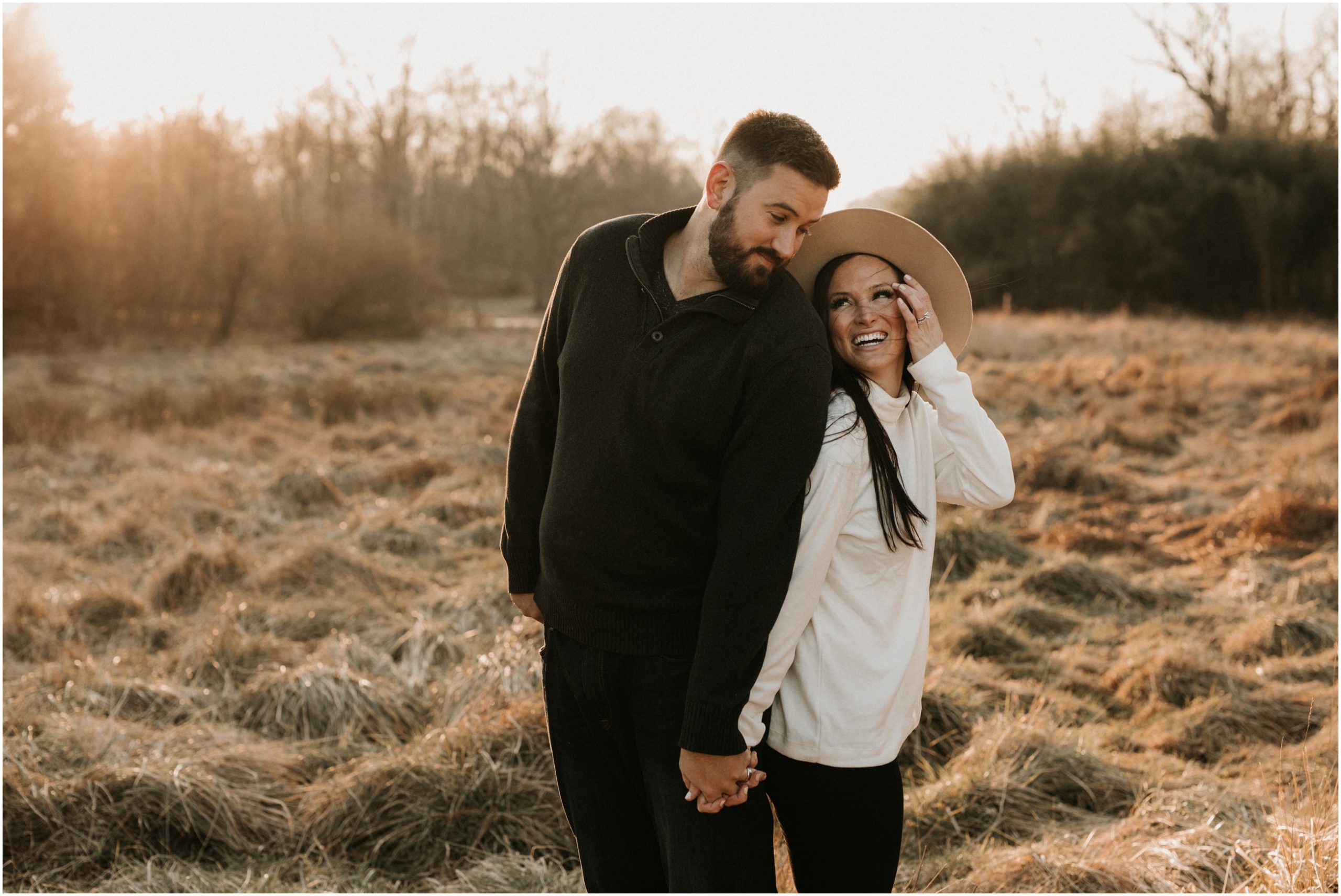 couple laughing while standing in golden field at sunset