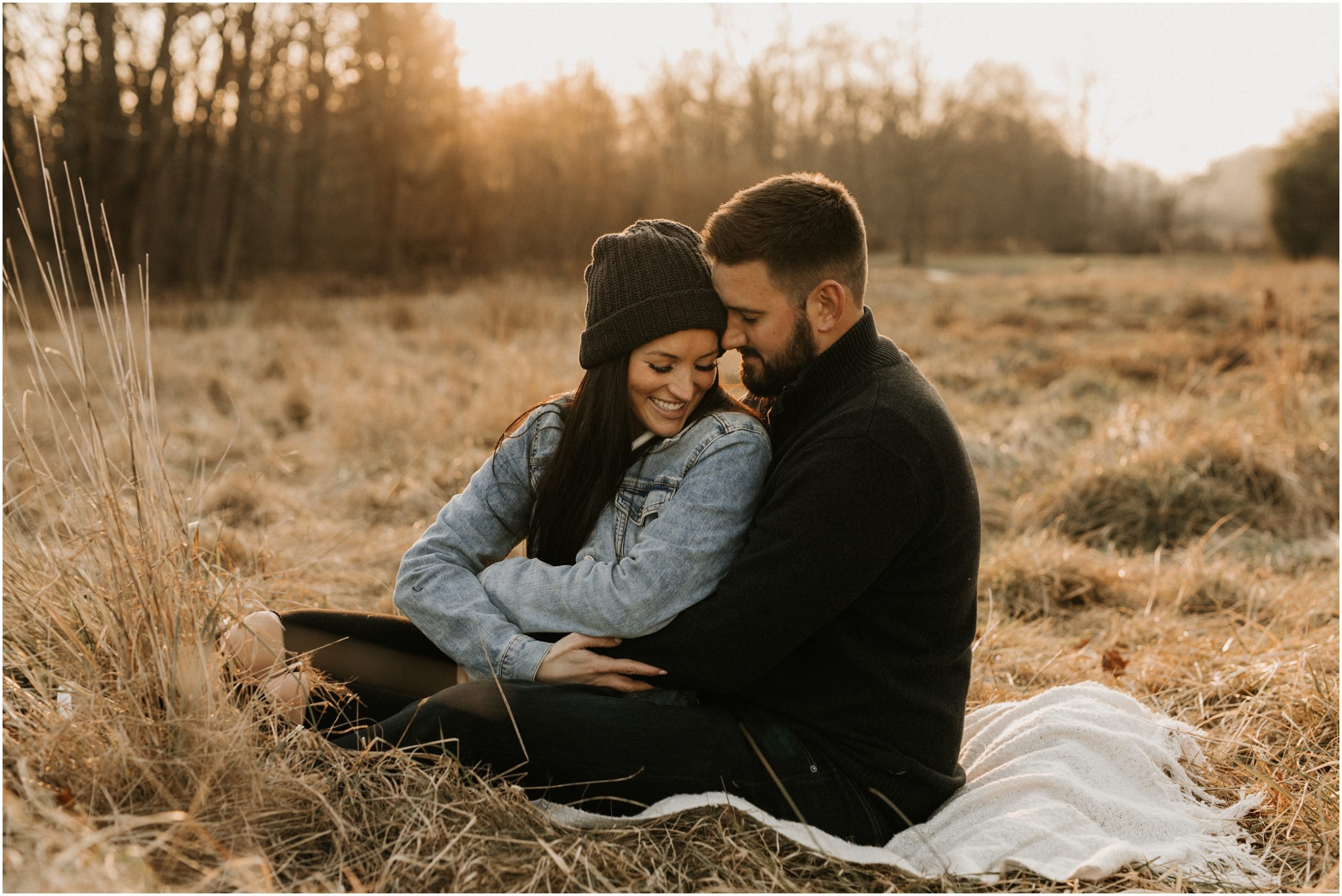couple cuddling up in field during sunset