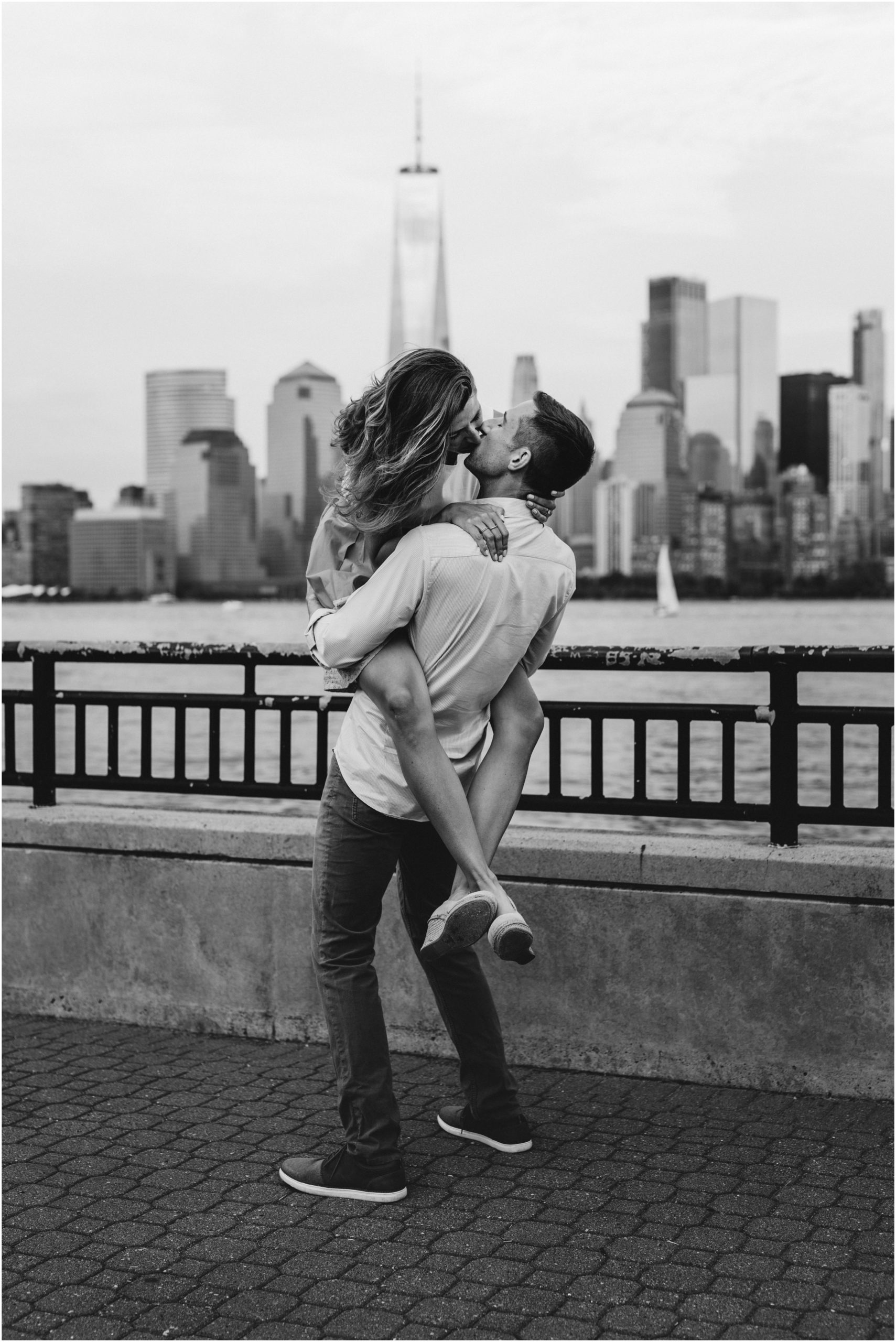 black and white image of girl jumping into guy's arms and kissing