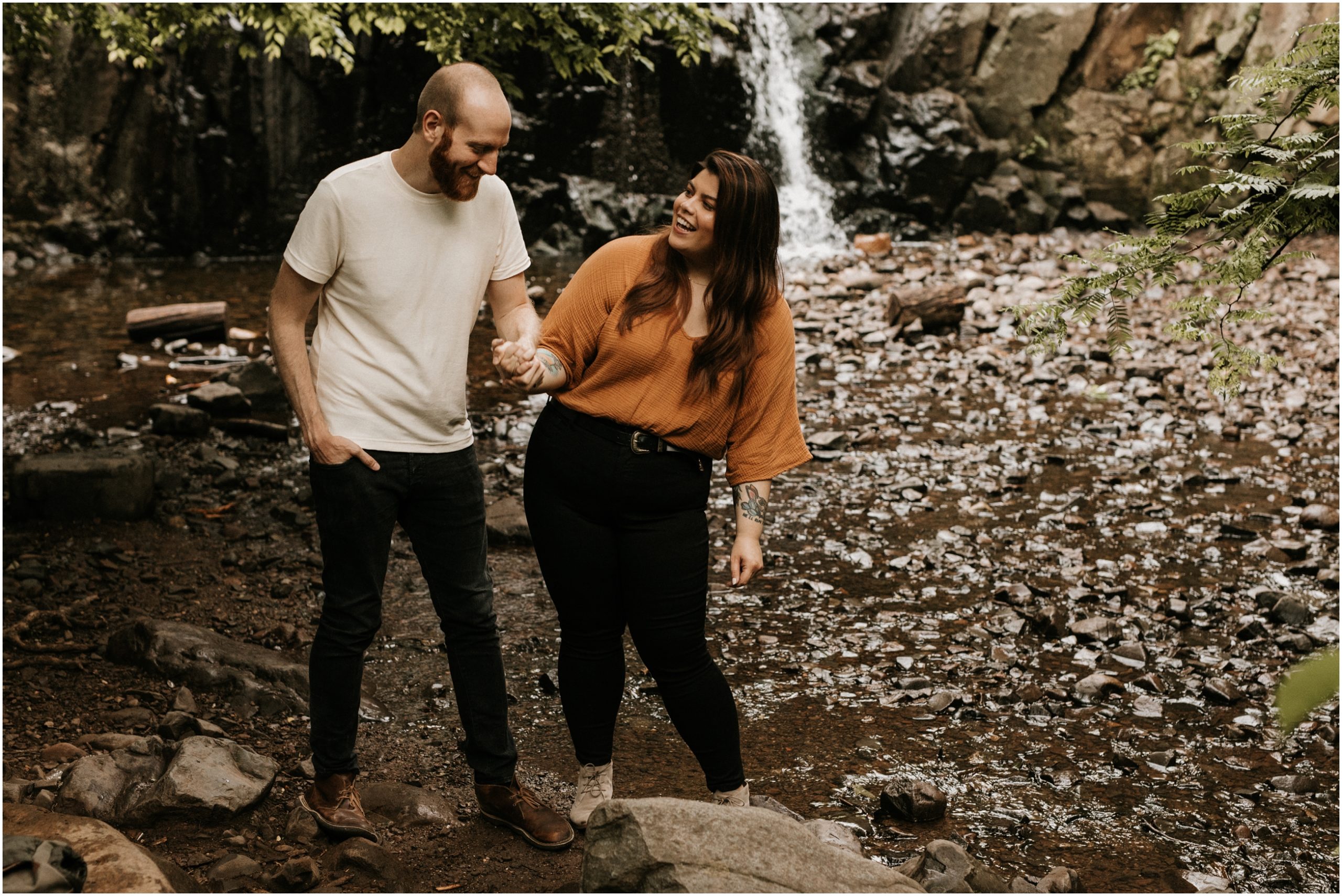 couple laughing in front of waterfall