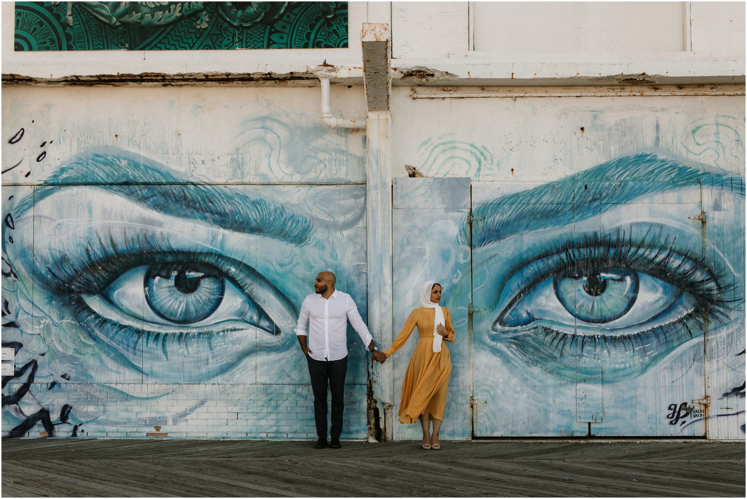 couple standing in front of mural of eyes