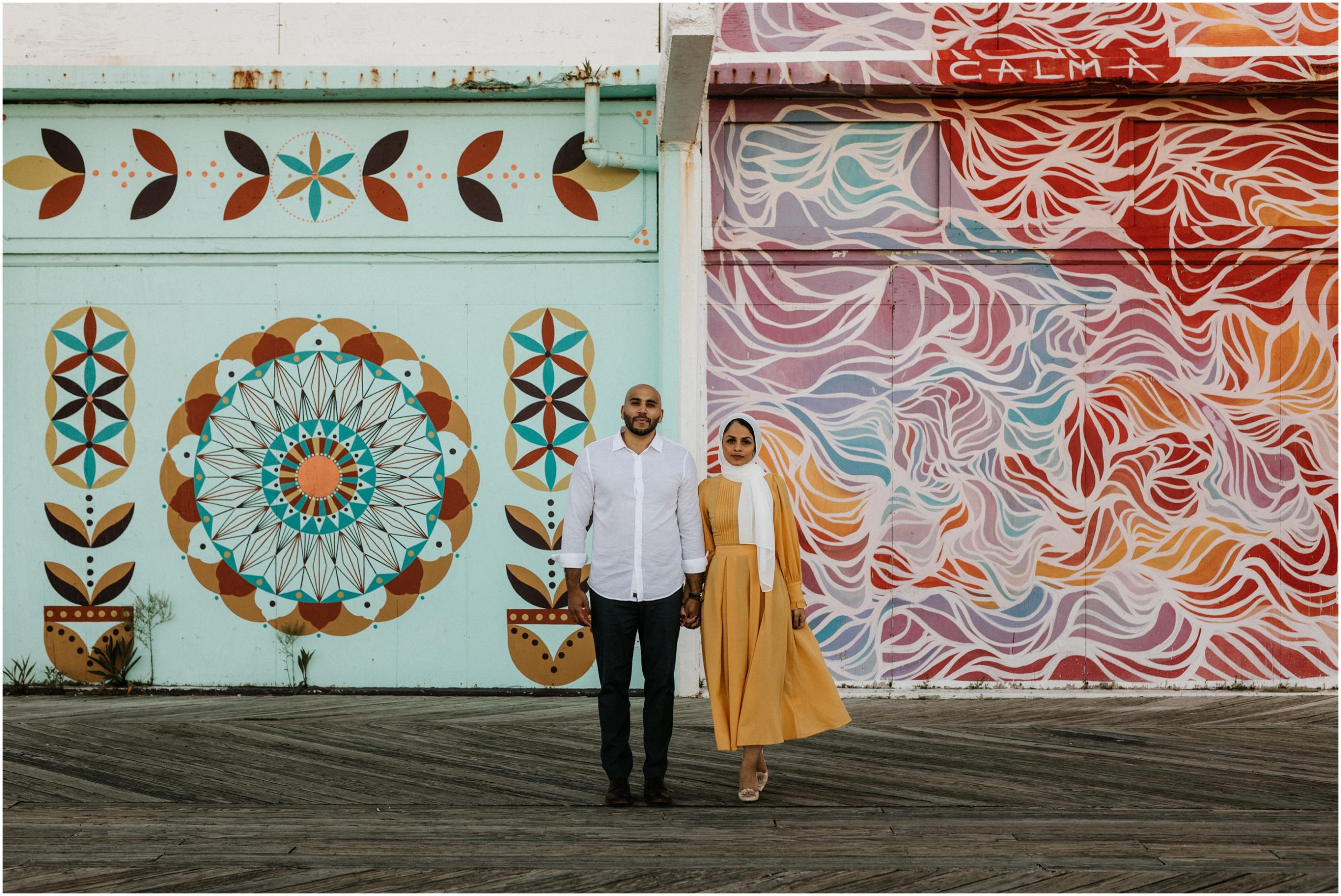 couple standing in front of murals on boardwalk in asbury park new jersey
