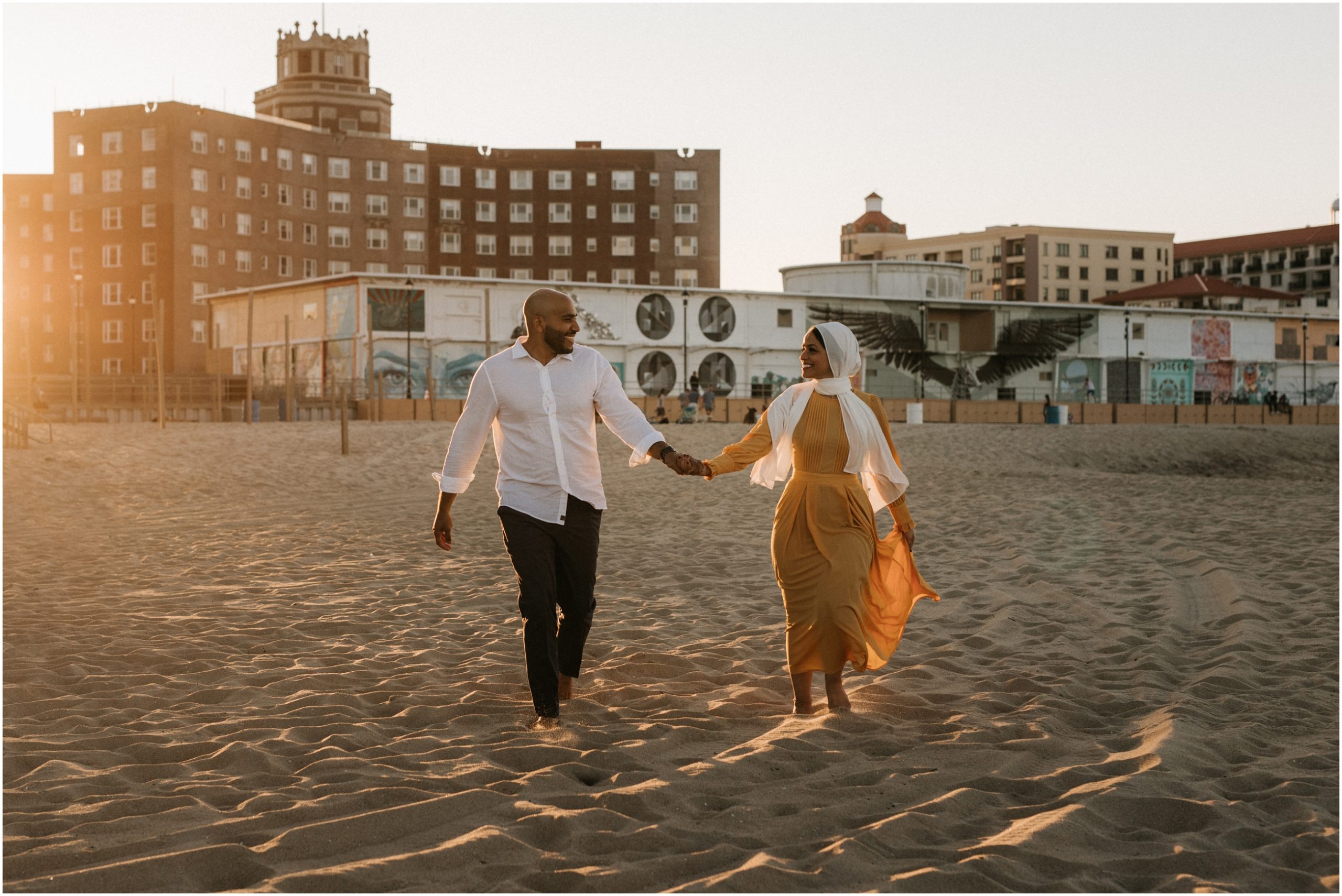 couple running on beach in asbury park new jersey at sunset