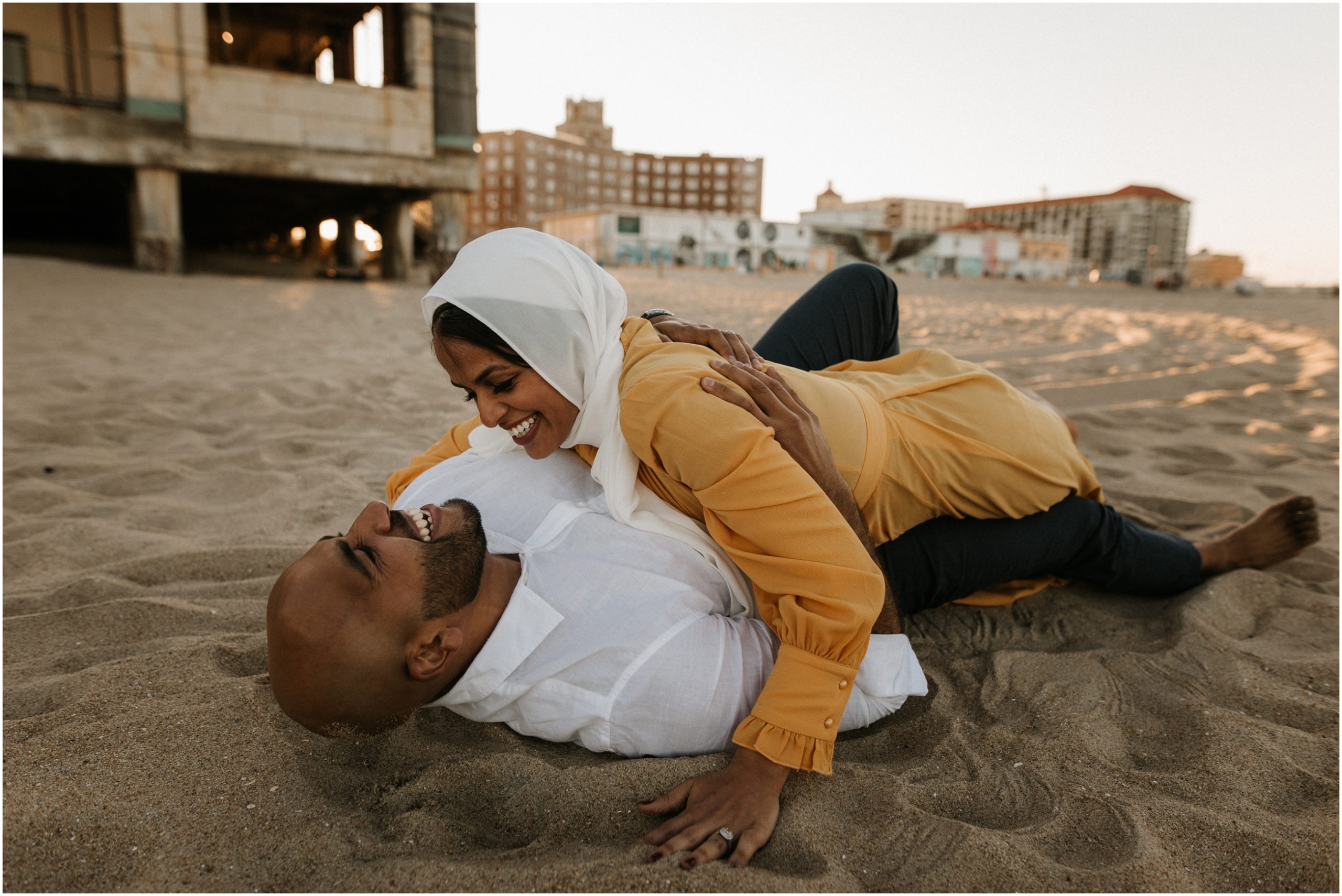 couple rolling around in sand on beach