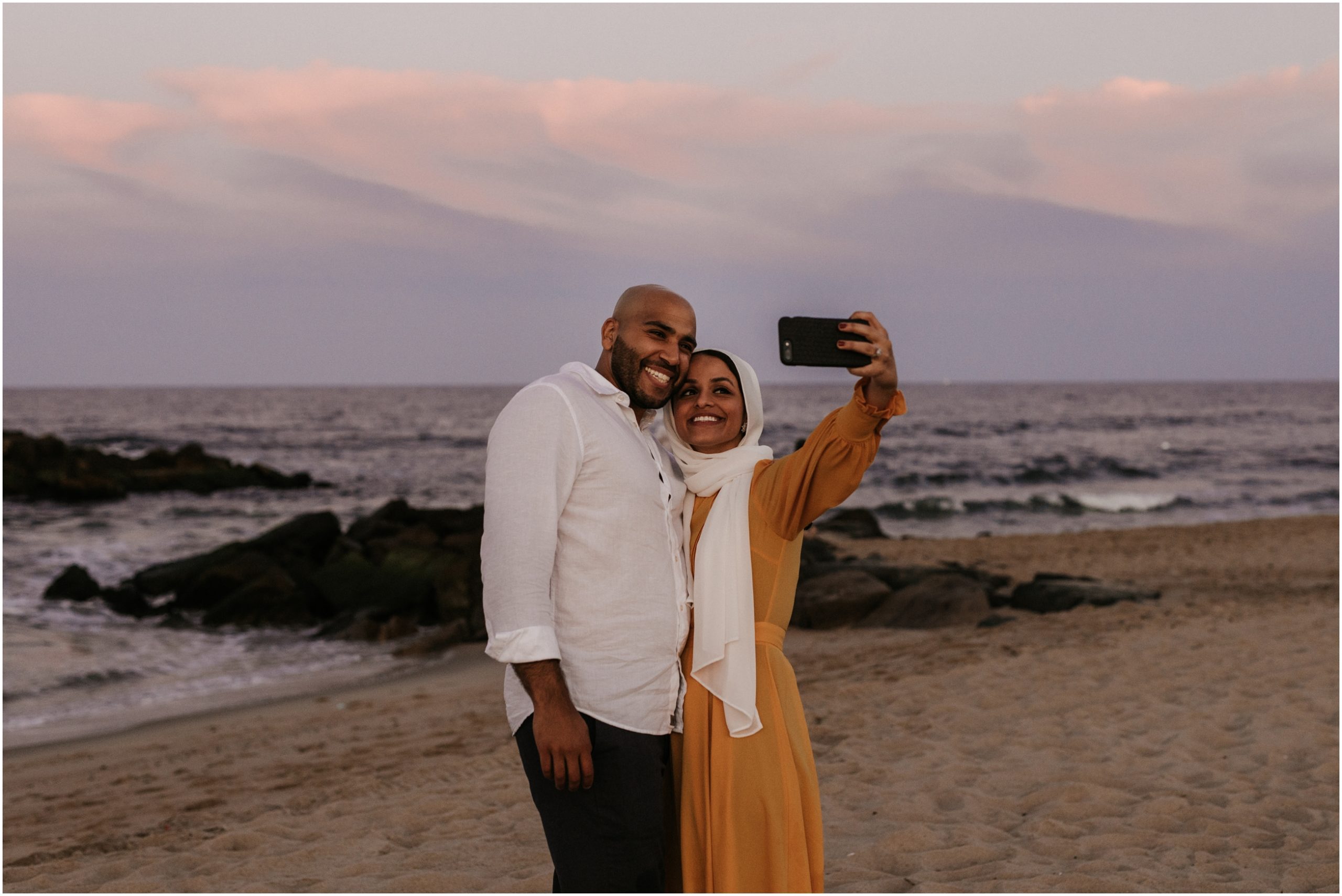 couple taking a selfie at sunset on beach in asbury park nj