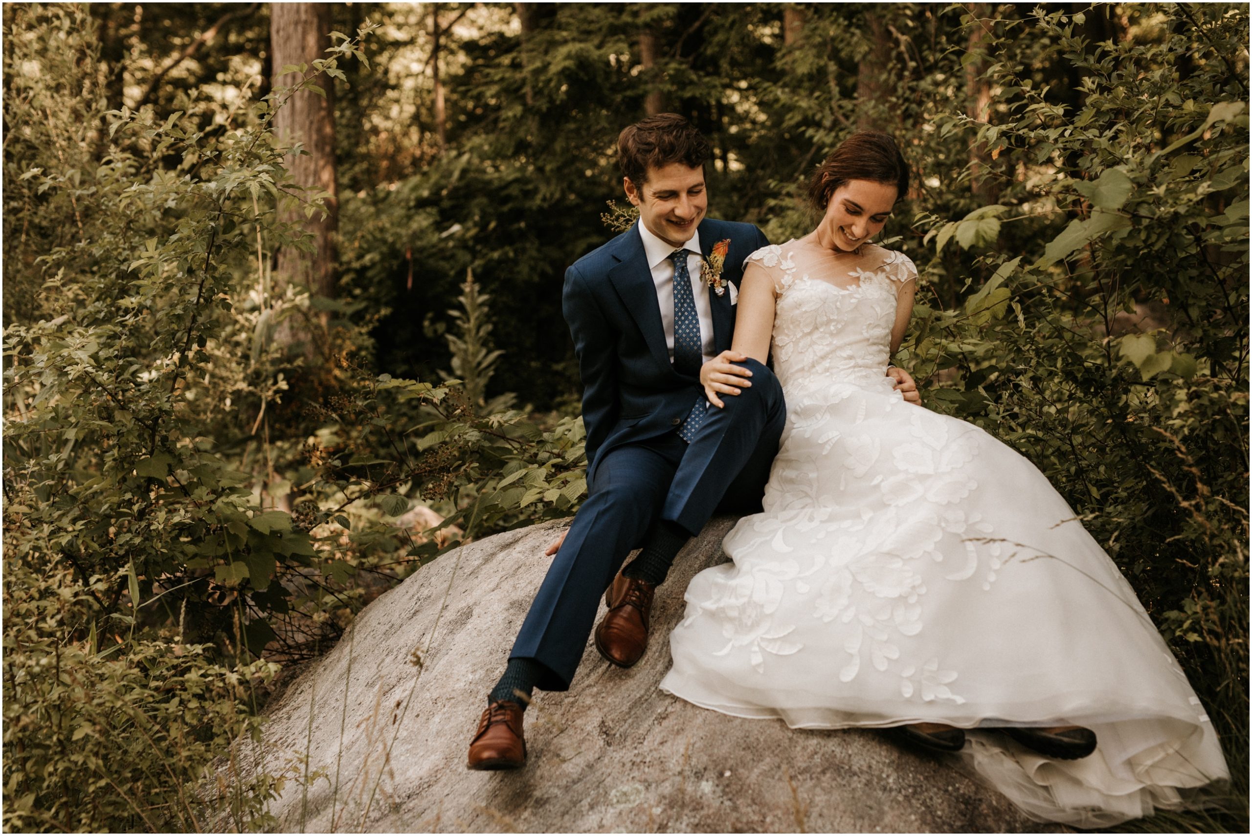 bride and groom sitting on rock