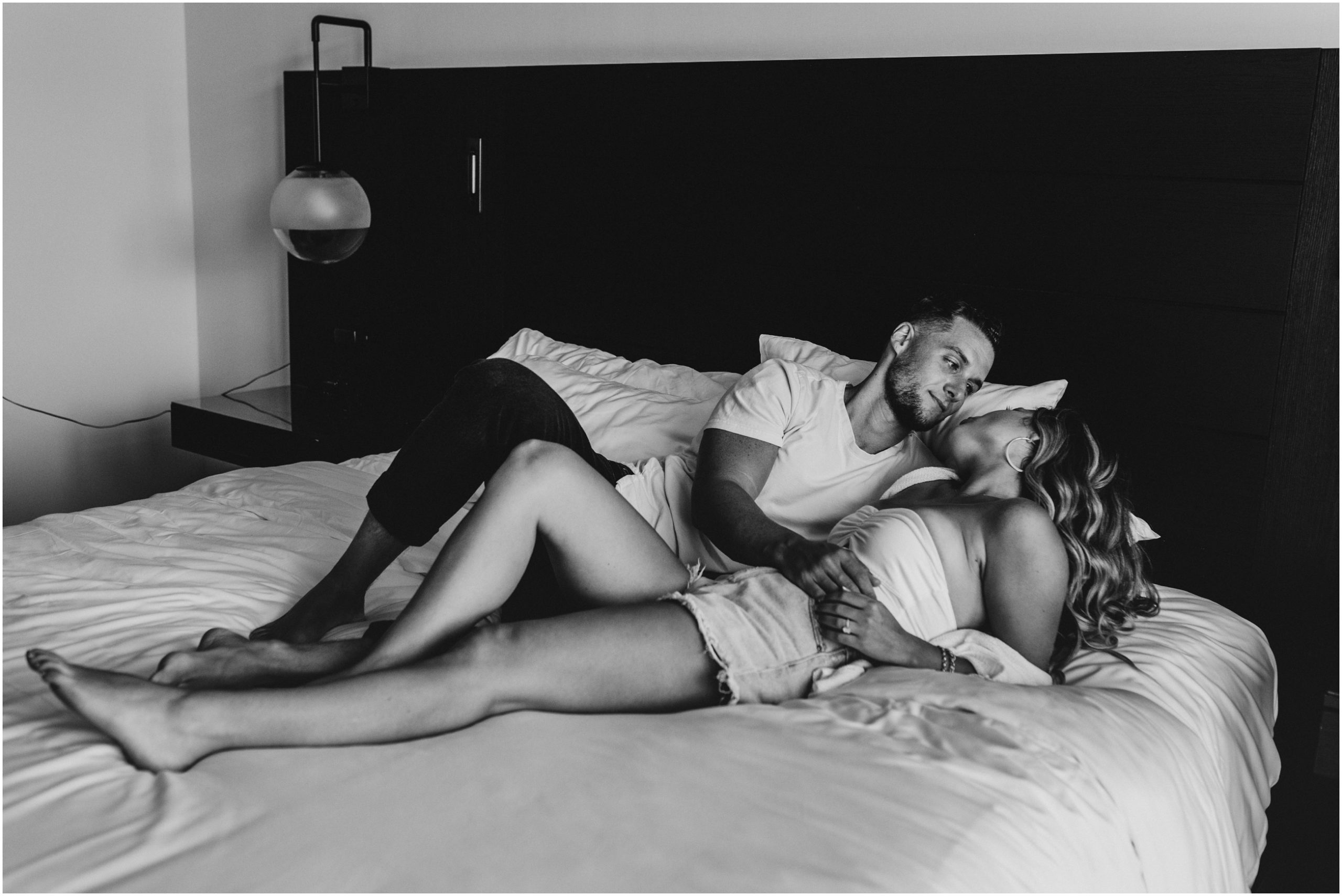 black and white image of couple cuddling in bed at wave resort in long branch new jersey
