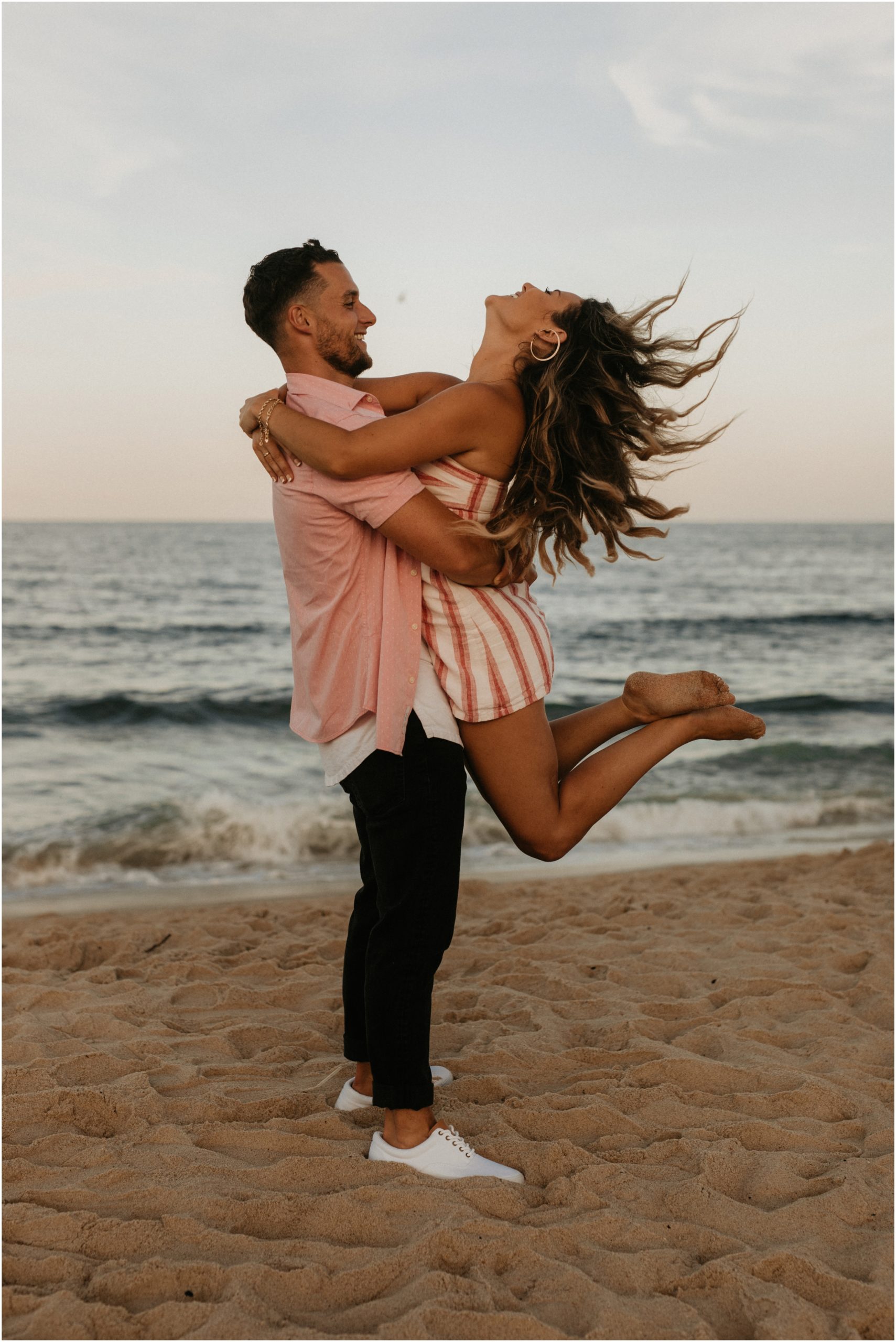man lifting woman on beach