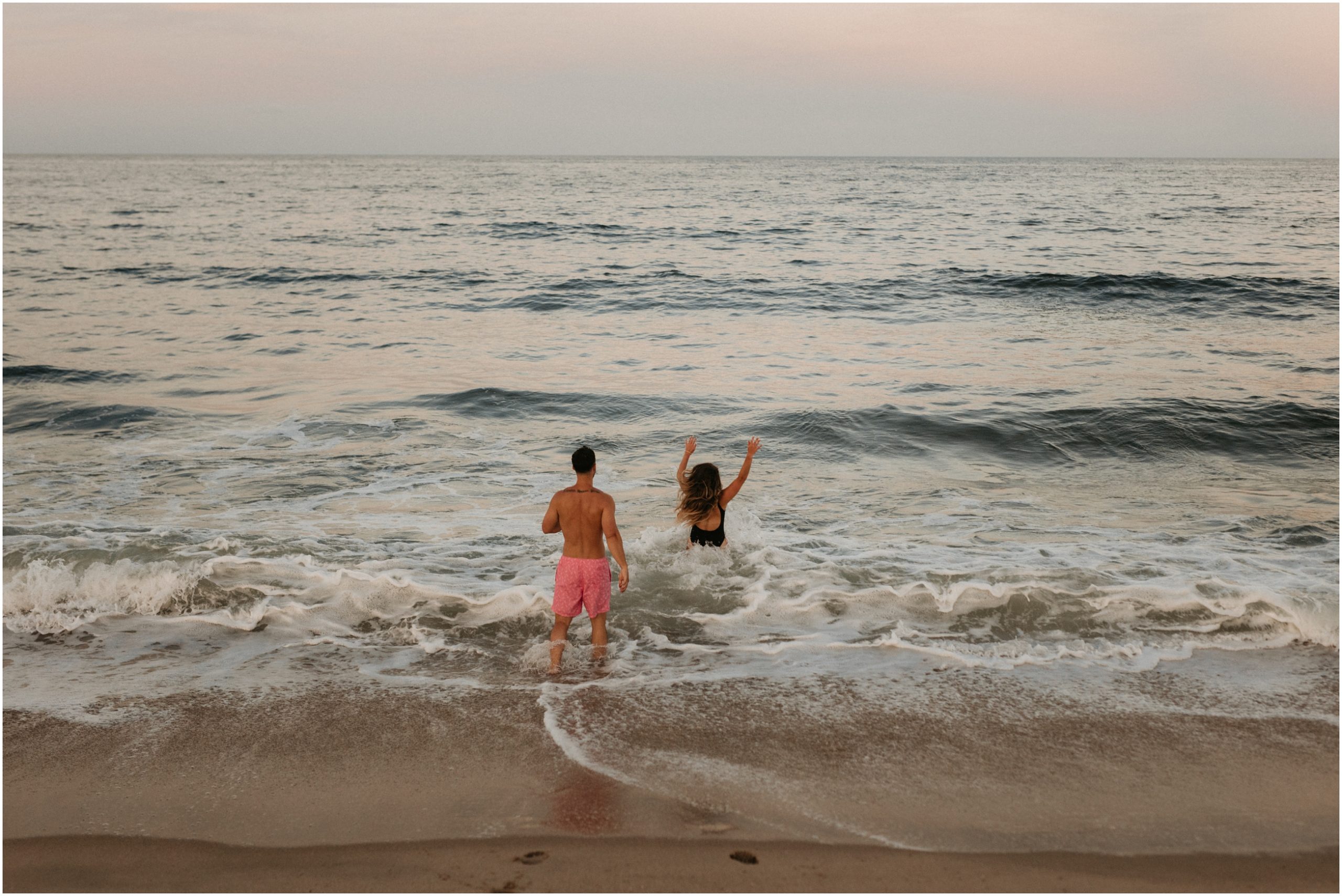 man and woman holding hands running into ocean in new jersey