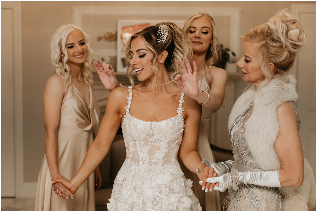 bride getting dressed with sisters