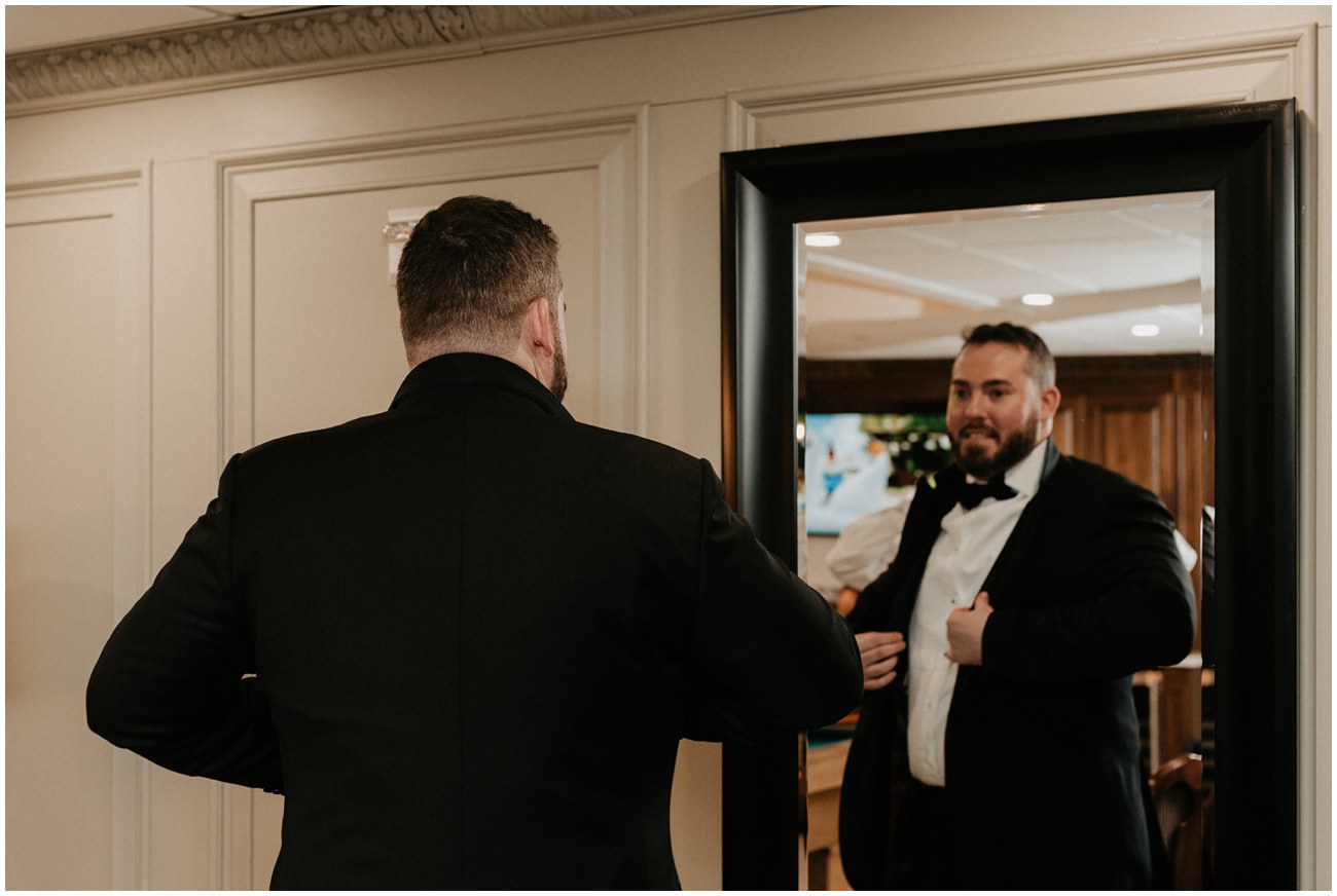 groom getting dressed and looking in mirror
