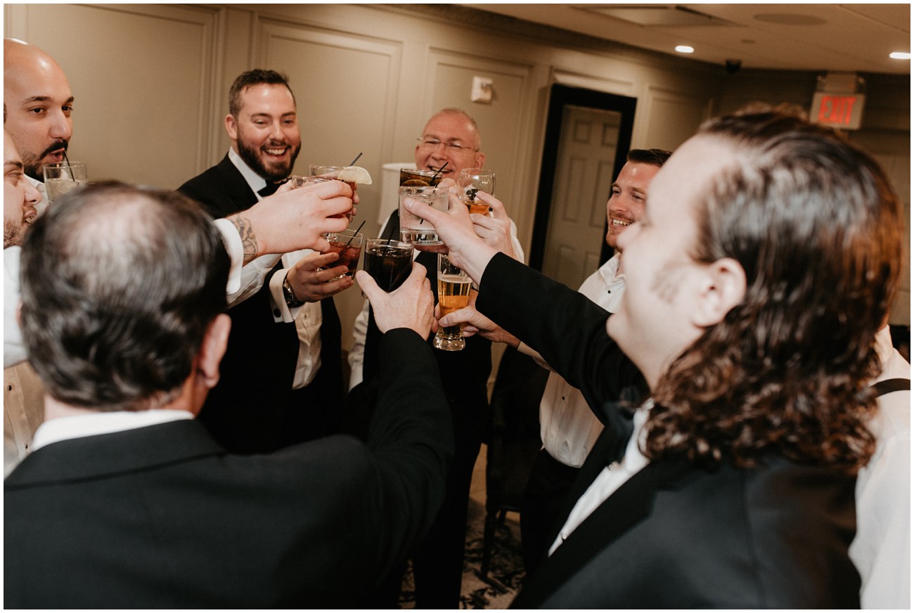 groom and groomsmen cheering cocktails