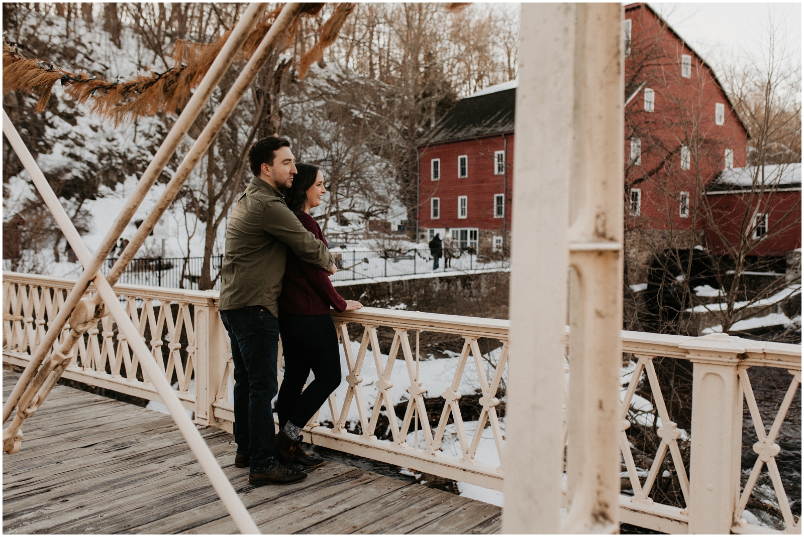 couple overlooking bridge in snow at red mill museum in clinton, nj