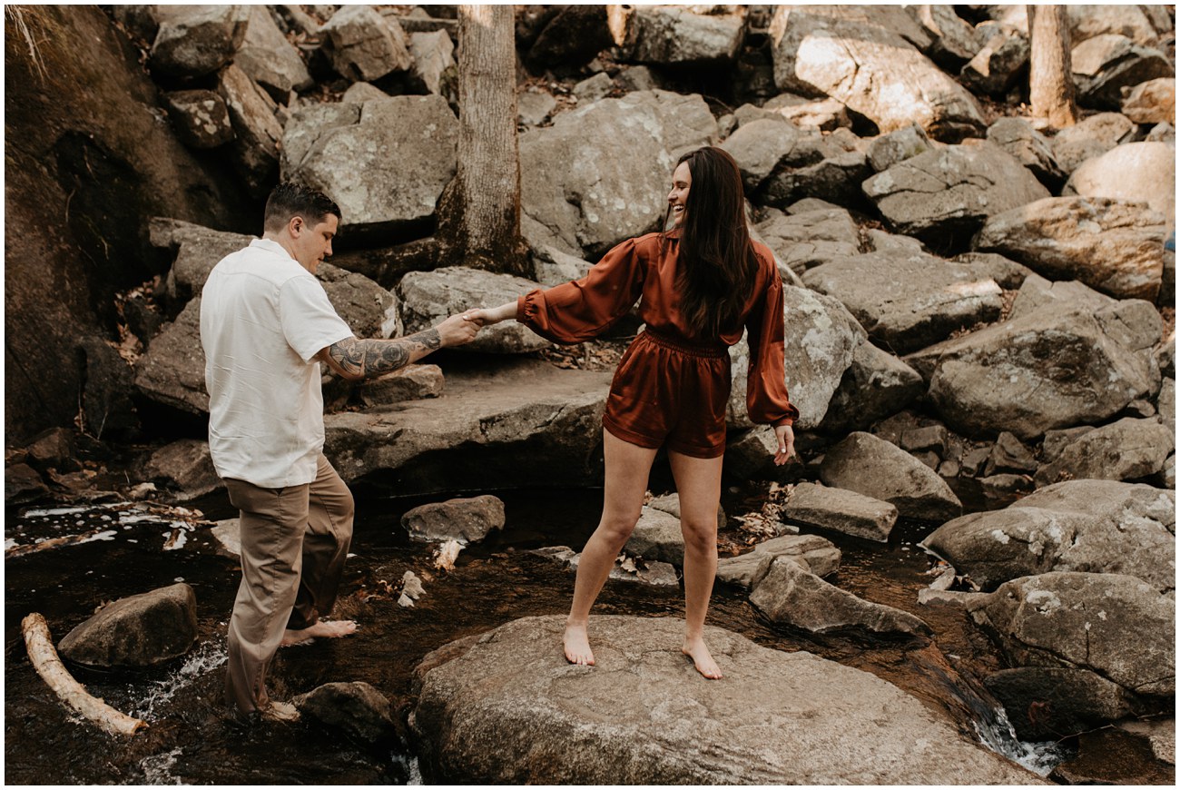 couple walking along rocks in a waterfall