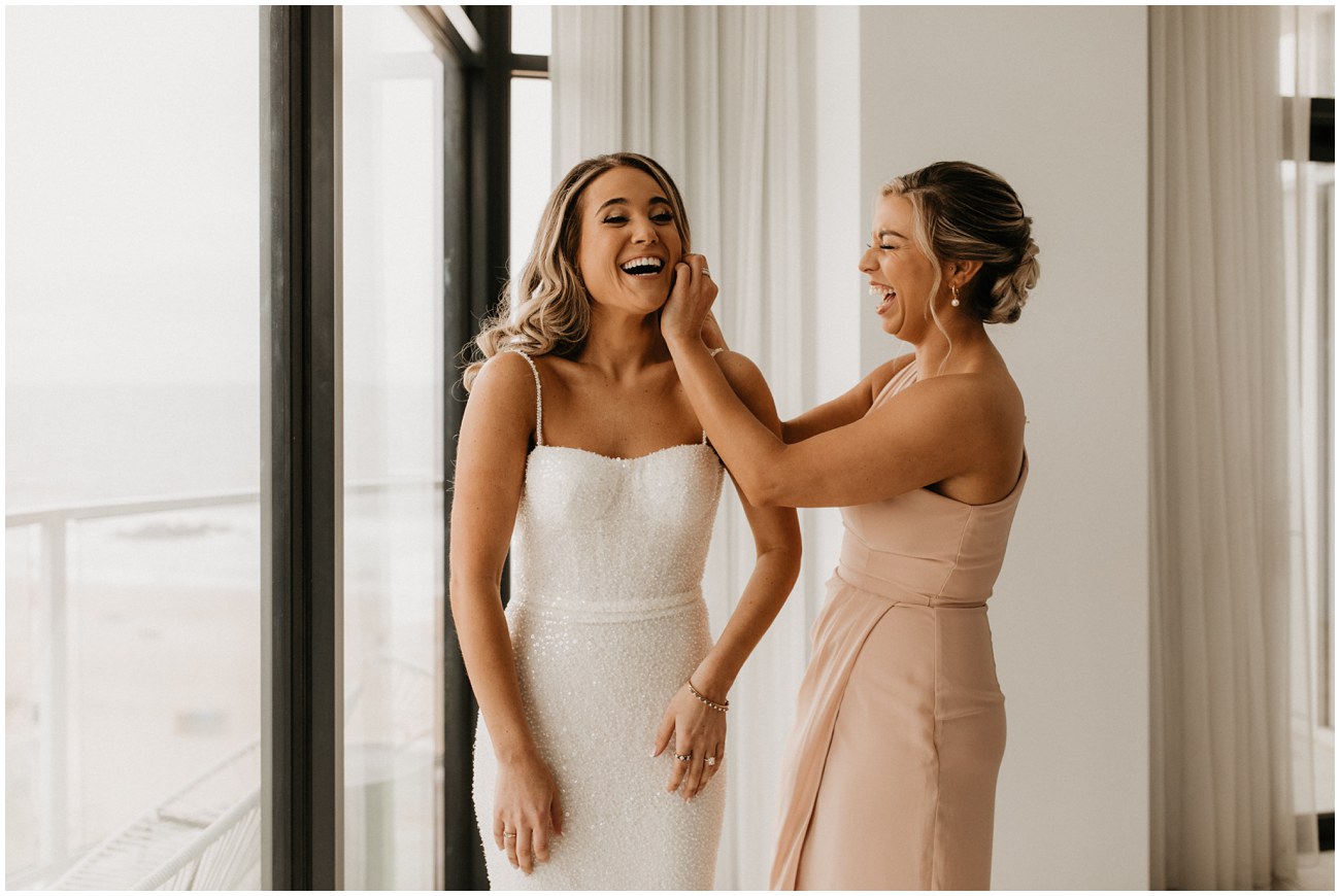 bridesmaid putting bride's earring on