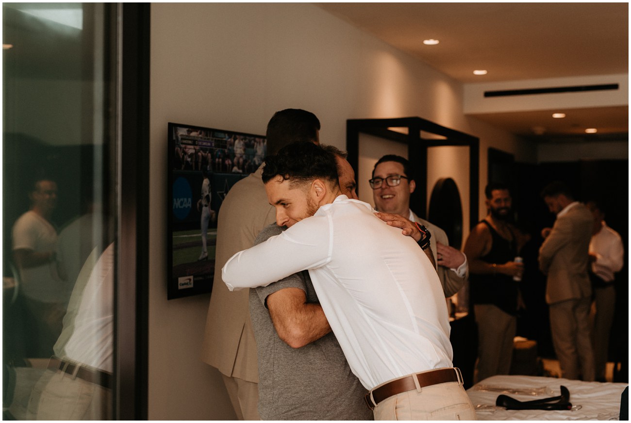 groom hugging friend in hotel room before wedding ceremony