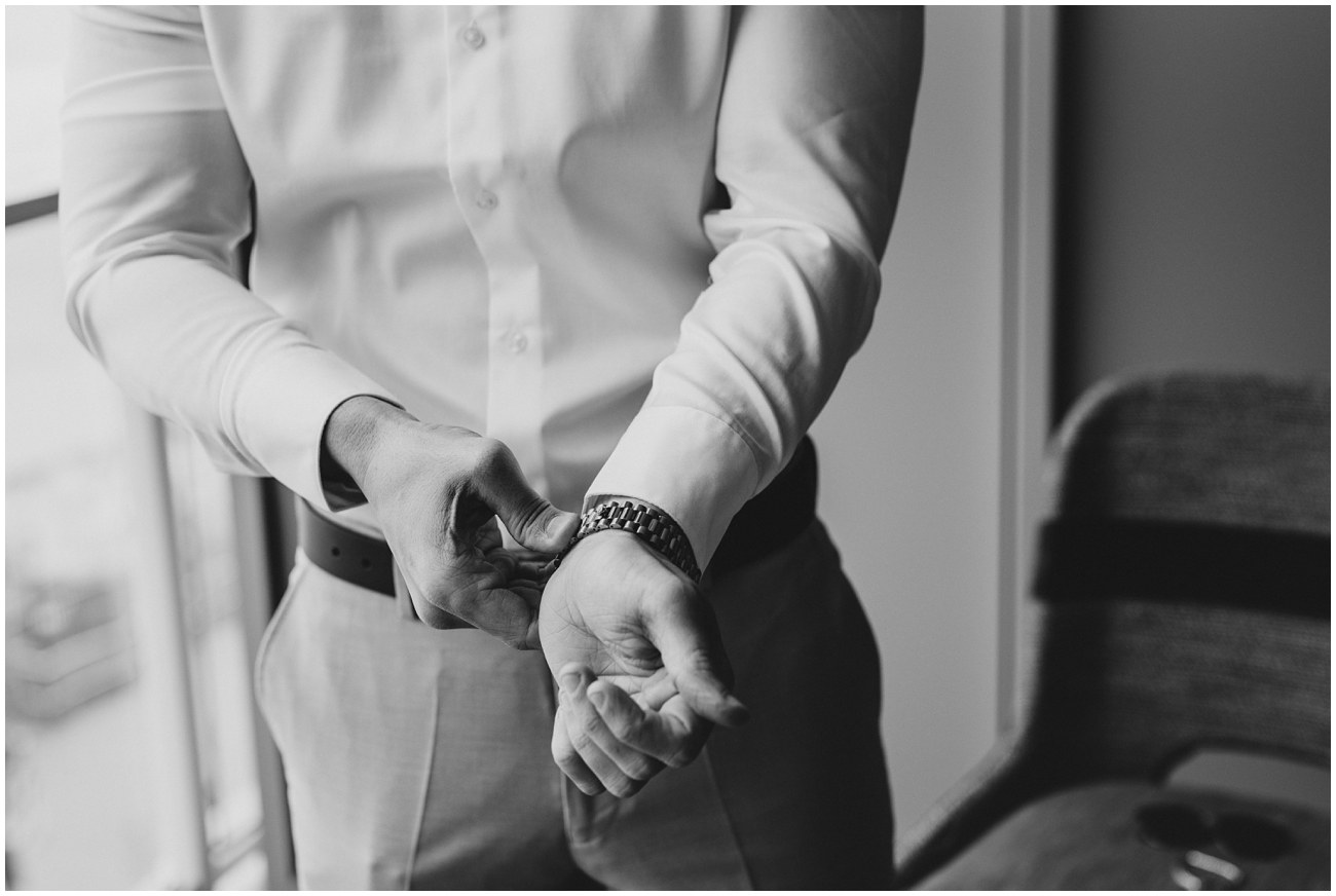 black and white image of groom putting watch on
