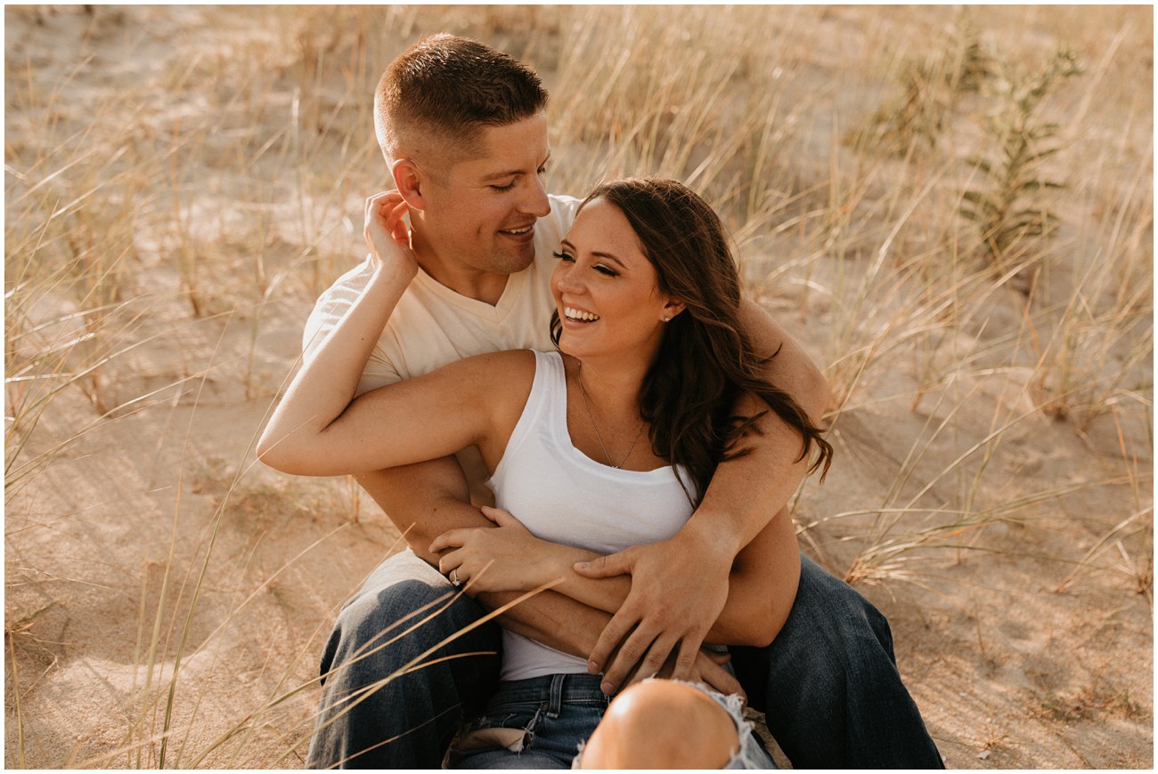 A couple embraces on the dune of Sea Girt beach for a romantic engagement shoot