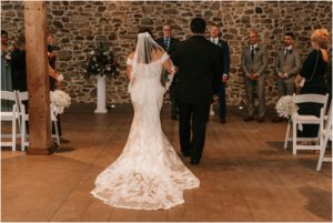 bride and father walking down aisle in barn