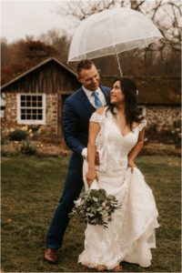 bride and groom portrait outside in rain with umbrella