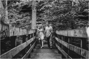 black and white image of couple walking across bridge
