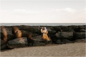 couple kissing and snuggling on jetty rocks in asbury park nj