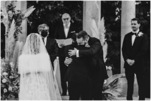 groom and father of groom hug at ceremony