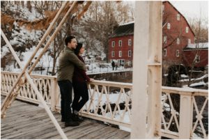 couple overlooking bridge in snow at red mill museum in clinton, nj