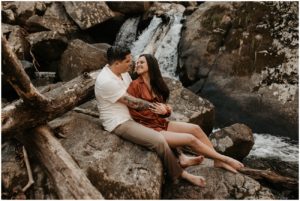 couples sitting on rocks in waterfall