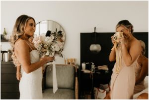 bridesmaid taking polaroid photo of bride