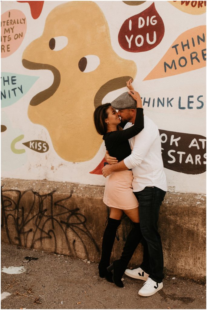 Couple embraces in front of mural wall for Philadelphia engagement session