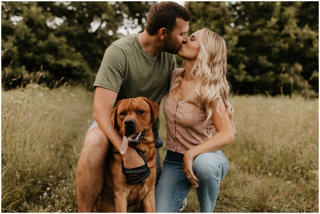 Couple shares kiss, joined by their dog, during engagement photo session
