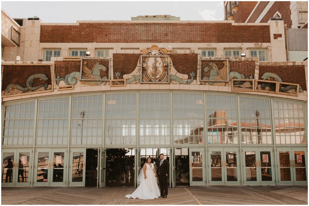 Bride and groom hold hands in front of historic Asbury Park building on the boardwalk
